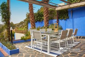 une table et des chaises blanches sur une terrasse avec un mur bleu dans l'établissement Villa Charma with private pool and Air conditioning close to sitges in peaceful location, à Olivella