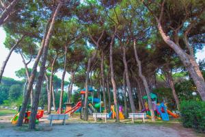 un parc avec une aire de jeux dotée de bancs et d'arbres dans l'établissement Le Primule, à Rosolina Mare