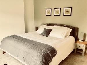 a bedroom with a large bed with two pictures on the wall at Eden Cottage in Frodsham