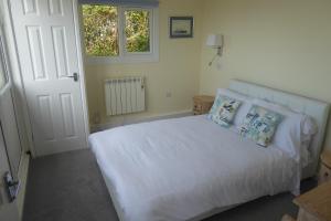 a bedroom with a white bed with pillows and a window at Pebble Lodges in Gurnard