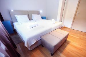 uma grande cama branca com um banco num quarto em Living In Aparthotel em Oradea