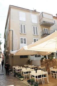 a restaurant with tables and umbrellas in front of a building at Aldo Apartments Center in Zadar