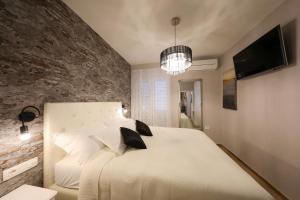 a bedroom with a white bed and a brick wall at Aldo Apartments Center in Zadar