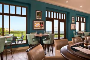 um restaurante com mesas, cadeiras e janelas em Hammock Beach Golf Resort & Spa em Palm Coast