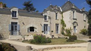 an old stone house with flowers in front of it at Manoir d'Orbé in Montreuil-Bellay