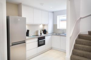 uma cozinha com armários brancos e um frigorífico de aço inoxidável em Citystay - Park House em Cambridge