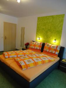 ein Schlafzimmer mit einem großen Bett mit orangefarbenen und gelben Kissen in der Unterkunft Gästehaus Bergrast in Schladming