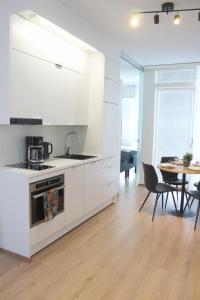 a kitchen with white cabinets and a table with chairs at Forenom Serviced Apartments Rovaniemi Valtakatu in Rovaniemi