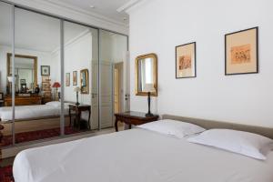 a bedroom with a white bed and a mirror at Veeve - Moments From Monet in Paris