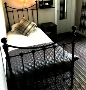 a black bed with a pillow on it in a room at West End Guest House in Kirkwall