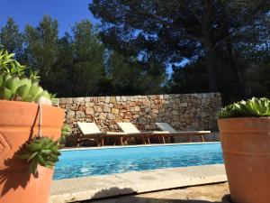 a swimming pool with chairs and a stone wall at Vila Familia Hvar in Vrboska