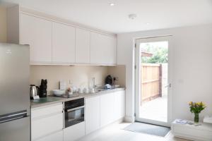 una cocina con armarios blancos y una puerta corredera de cristal en Citystay - Park House, en Cambridge