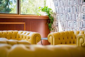 a row of yellow chairs in a room with a window at Hotel The Brand in Rome