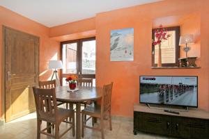 a dining room with a television and a table with chairs at Très bel appartement 4 pers Chalet Les Lupins - Les 2 Alpes in Les Deux Alpes