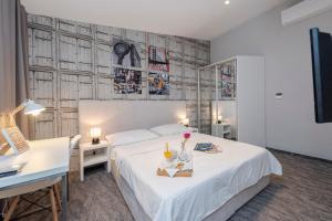 a bedroom with a white bed and a desk and a desk at Downtown Boutique Hostel in Zadar