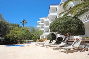 a row of lounge chairs in front of a building at Aparthotel Niu d´Aus in Portopetro