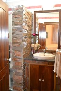 a bathroom with a stone wall next to a sink at Monte da Floresta B&B in Ferreira do Alentejo