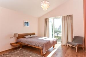 a bedroom with a bed and a chair and a window at Atsipūskit in Palanga