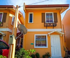 een oranje huis met een witte deur en een balkon bij Hillview Apt w/ Pool Access - Free Wifi in Tagbilaran-stad