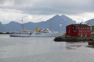 a cruise ship in the water next to a red building at Nyksund Appartement, Nyksund Brygge in Nyksund