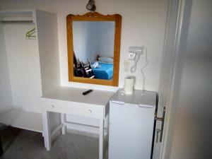 bagno con specchio e mobile con lavabo bianco. di Hotel Perissa a Perissa