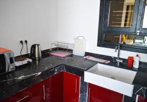 cocina con armarios rojos y encimera negra en Bouad Luxury Apartment, en Taghazout