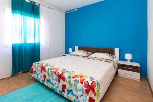 een slaapkamer met een bed met een blauwe muur bij Apartments Luka in Pag