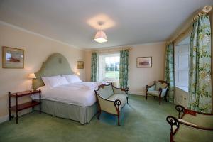 a bedroom with a bed and two chairs and a window at Glamis House in Forfar