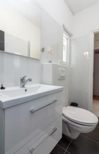 a white bathroom with a toilet and a sink at Apartments Luka in Pag