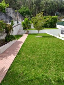 een tuin met groen gras en bomen en een stoep bij CasaJP in Viana do Castelo