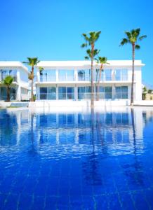 duży basen z palmami przed budynkiem w obiekcie Lysithea Hotel w Larnace