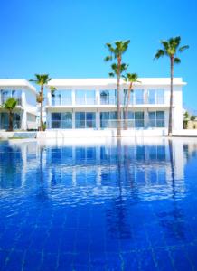 a large swimming pool with palm trees in front of a building at Lysithea Hotel in Larnaca