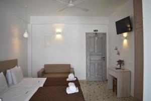 Habitación con cama, sofá y TV. en Andriani's Guest House, en Mykonos ciudad