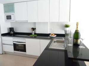 a white kitchen with a sink and a bottle of wine at Las Azaleas in San Juan de los Terreros