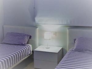 1 dormitorio con 2 camas y mesita de noche con lámpara en Las Azaleas, en San Juan de los Terreros