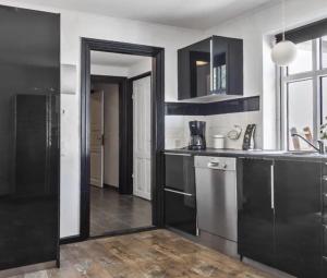 a kitchen with black cabinets and stainless steel appliances at Nilles bed & breakfast in Ølgod