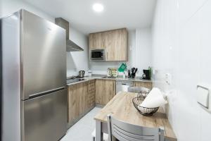 una cucina con tavolo in legno e frigorifero in acciaio inossidabile di APARTAMENTO CONVENTO ENCARNACIÓN ad Antequera