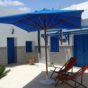 un paraguas azul sentado junto a una silla y una silla en Dar El Goulli, en Hammam Sousse