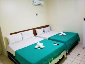 - deux lits assis l'un à côté de l'autre dans une pièce dans l'établissement Pousada Catamarã Praia de Pajuçara, à Maceió