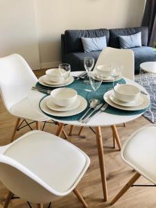 a white table with chairs and plates and wine glasses at Modern Flats in Kielce