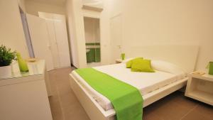 a white bedroom with a green blanket on a bed at Hotel Novecento in Scicli