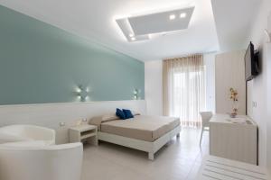 um quarto branco com uma cama e uma televisão em Alfema Rooms em Ugento