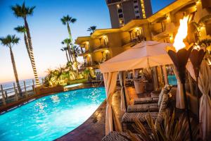 a pool at a hotel with chairs and an umbrella at Pacific Terrace Hotel in San Diego