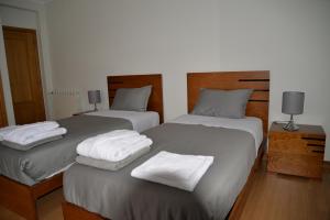 2 bedden in een slaapkamer met witte handdoeken bij CasaJP in Viana do Castelo