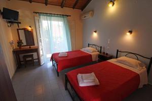 a hotel room with two beds and a television at Dimitris Studios Acharavi Corfu in Acharavi