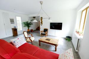 a living room with a red couch and a table at La Maison du Parc Affaires et Tourisme in Crépy-en-Valois