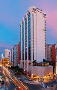 un edificio blanco alto en una calle de la ciudad con tráfico en Libertador Hotel en Buenos Aires