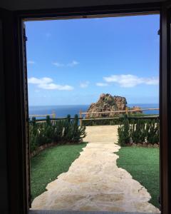 una vista da una porta che si affaccia sull'oceano di Il Tramonto Tanca Piras a Nebida