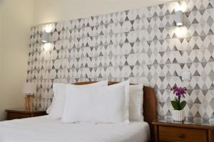 a bedroom with a white bed with a checkered wall at Hotel Visconde in Porto