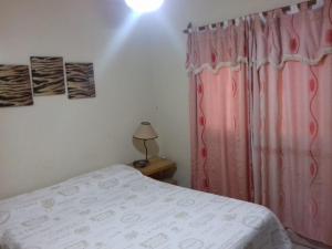 a bedroom with a bed and a pink curtain at Hotel POSTA NORTE in Posadas